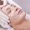 A young female getting skin mask treatment on her face with massage glove